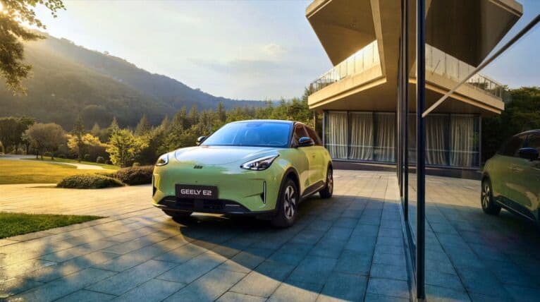 Geely E2 verde visto de frente junto a una vivienda moderna